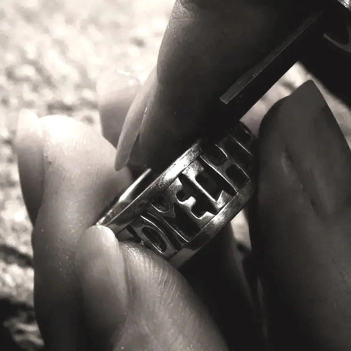 Close-up of the jeweller’s hand holding the sterling silver Alfred Ring along with an engraving tool