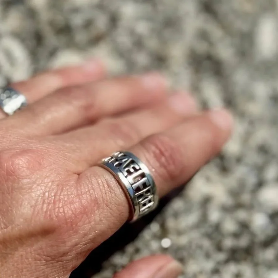 An Anglo-Saxon inspired hand-formed sterling silver ring on a woman’s hand resting on a rock