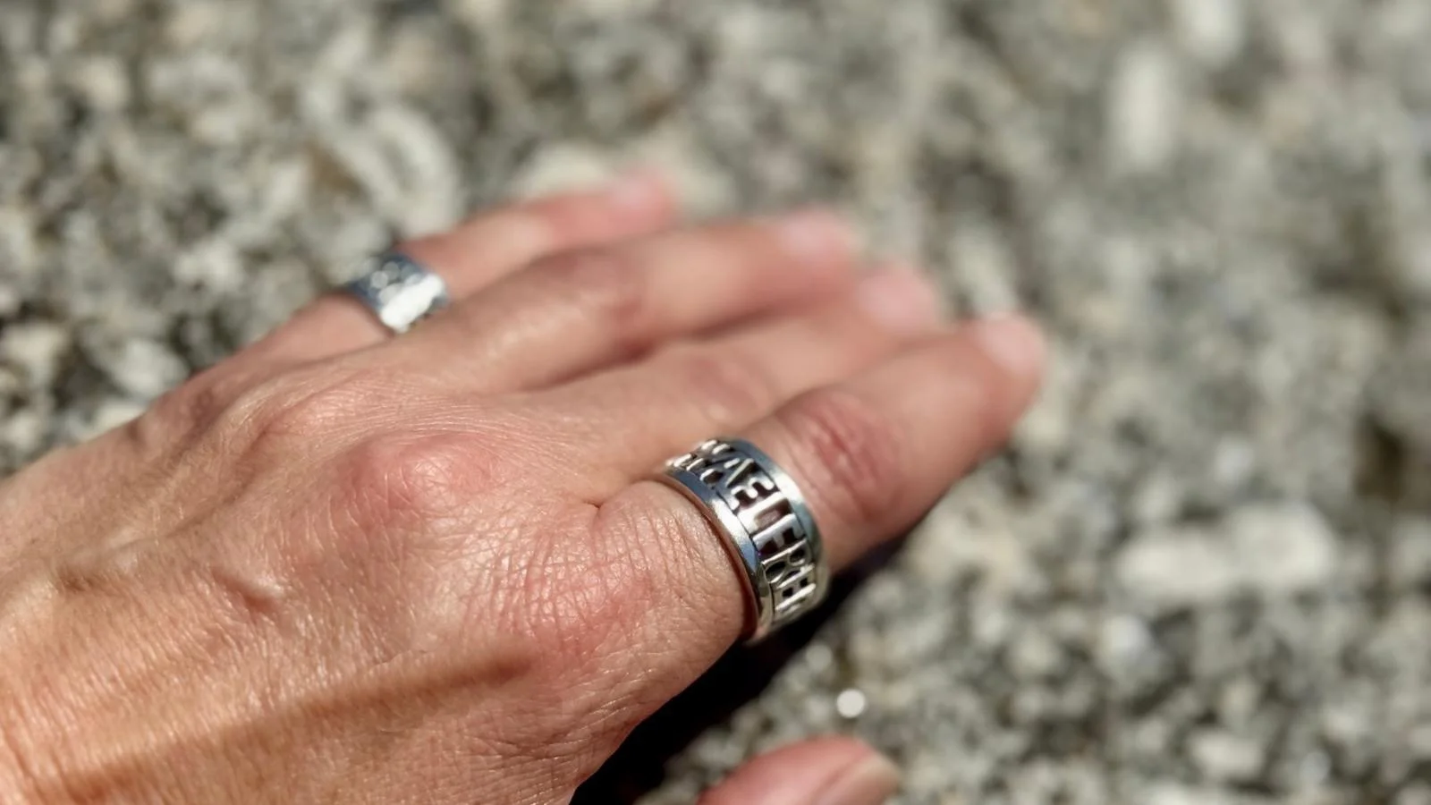 An Anglo-Saxon inspired hand-formed sterling silver ring on a woman’s hand resting on a rock
