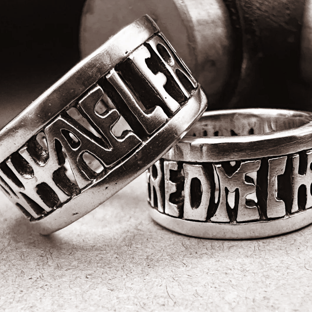 Two handmade Anglo-Saxon and Viking-age sterling silver rings with a Thor’s hammer in the background