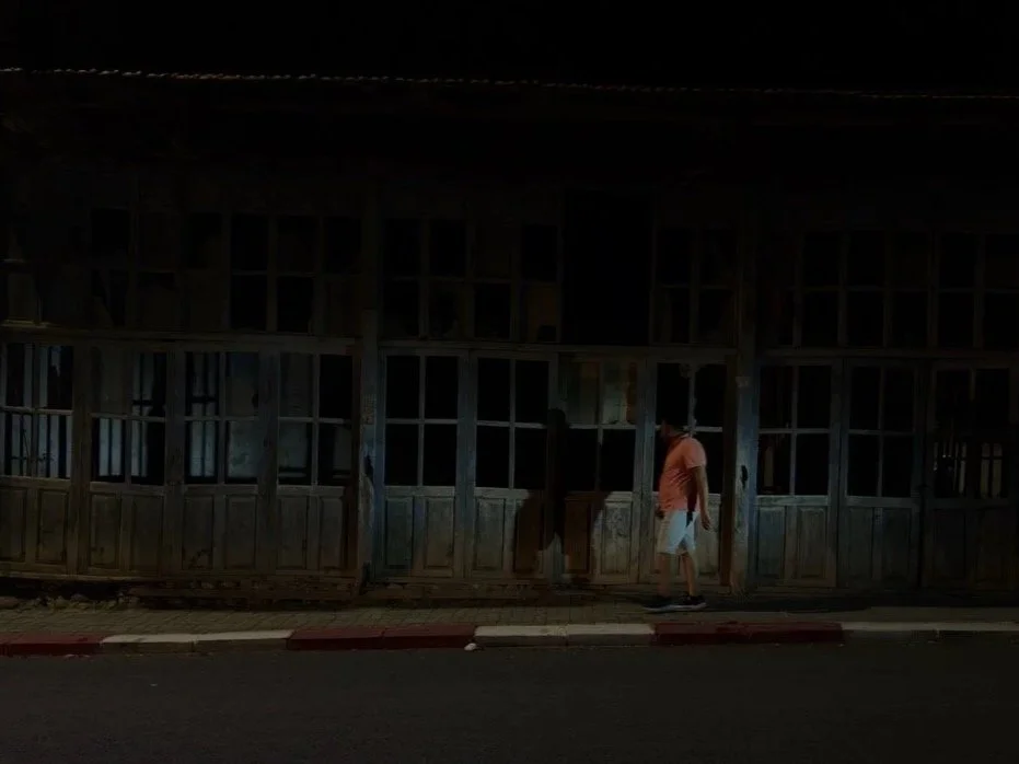 Mann spaziert vor verfallenem Haus mit Schatten