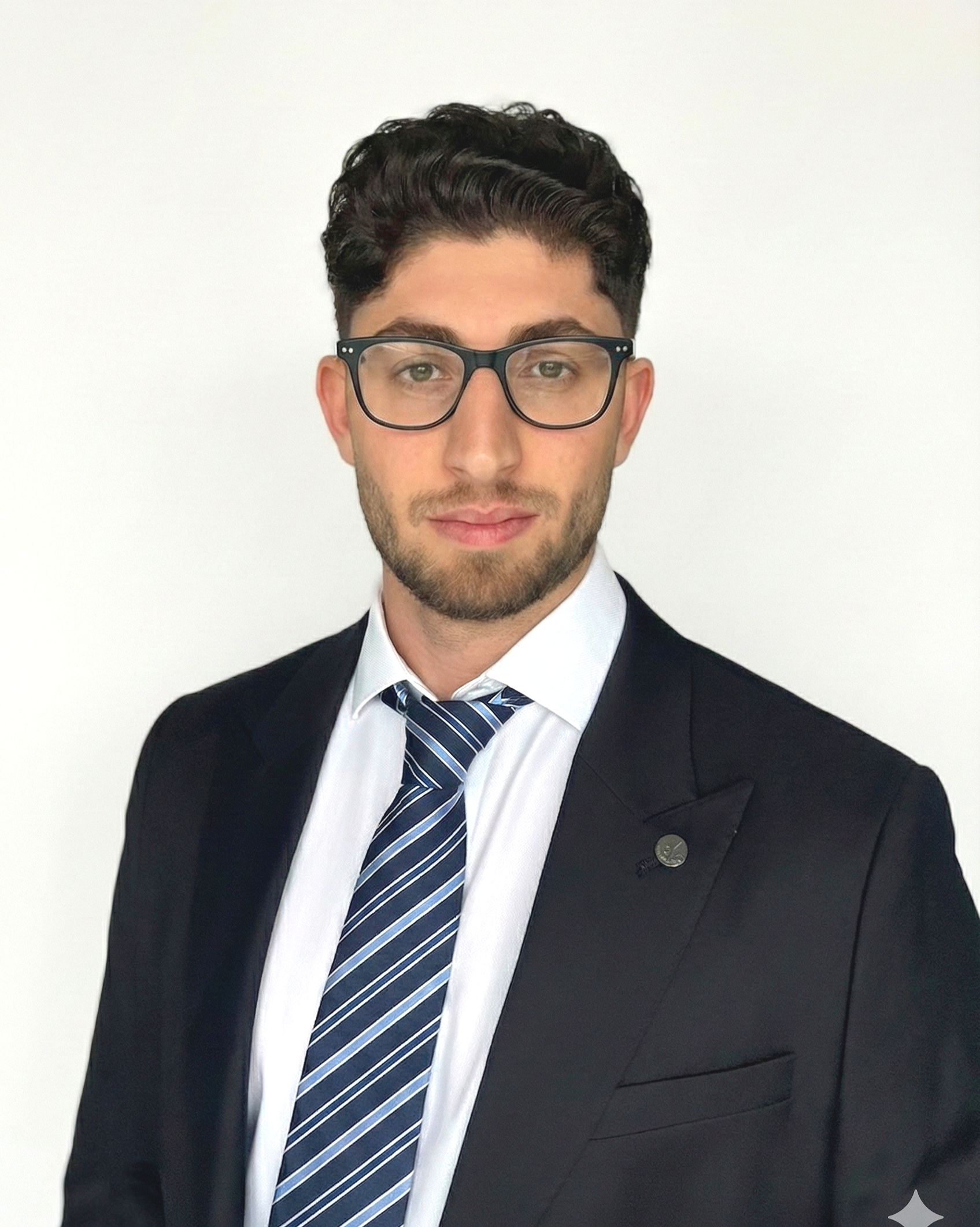 Porträt eines jungen Mannes mit dunklen Haaren, Brille, Business-Anzug, weißem Hemd und gestreiftem Krawatte vor weißem Hintergrund.