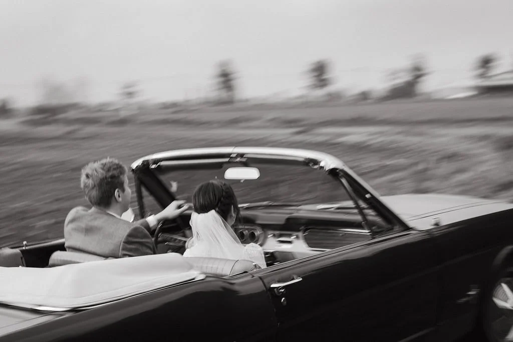 Bride and Groom driving a vintage car in Belgian countryside_black and white photo with motion blur.jpg