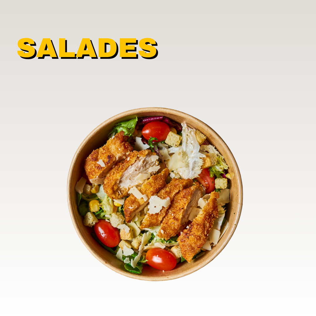 Salade dans un bol avec des morceaux de poulet frit, des tomates cerises, du maïs, de la laitue, du parmesan râpé, et des croûtons. Menus halal