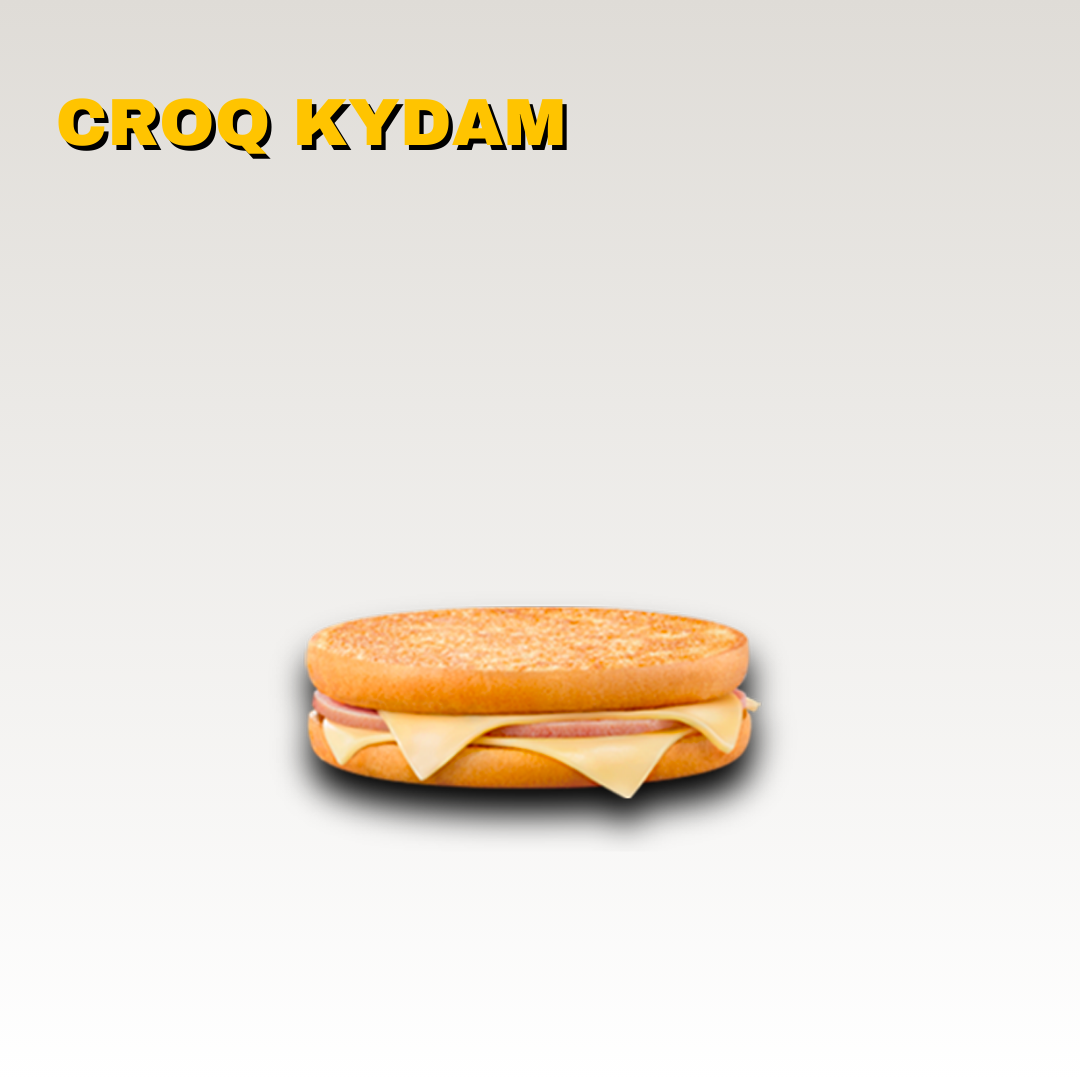 Un sandwich avec du fromage, du jambon de dinde, et un pain rond, avec texte jaune en haut qui dit 'CROQ KYDAM'. Toute notre carte est halal.