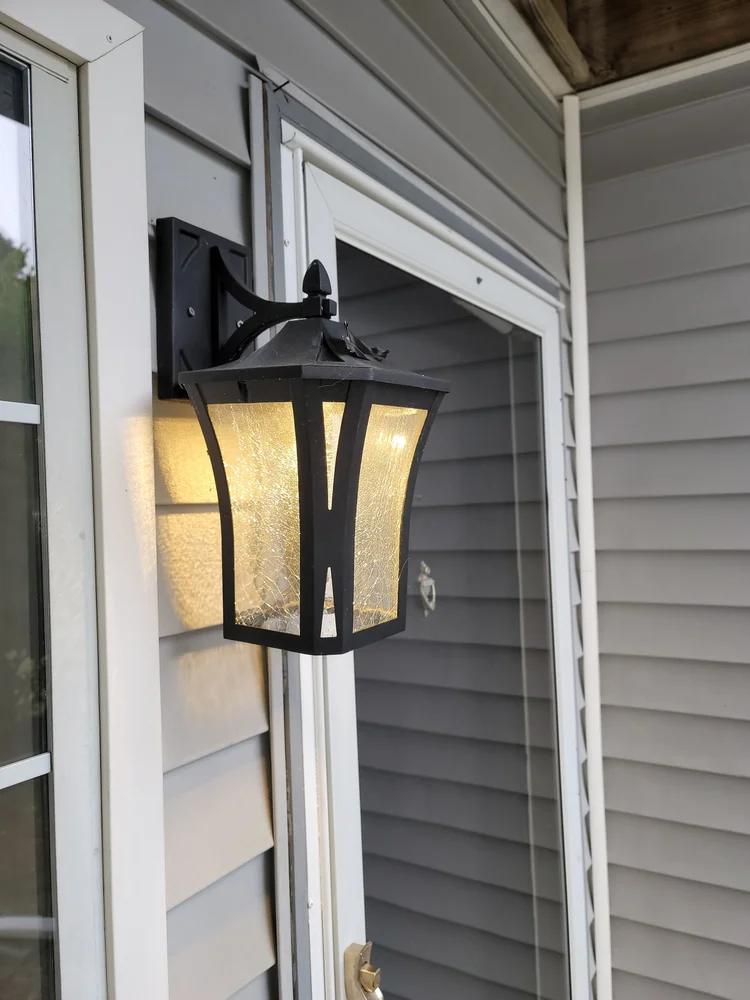 Illuminated black lantern beside a front entry