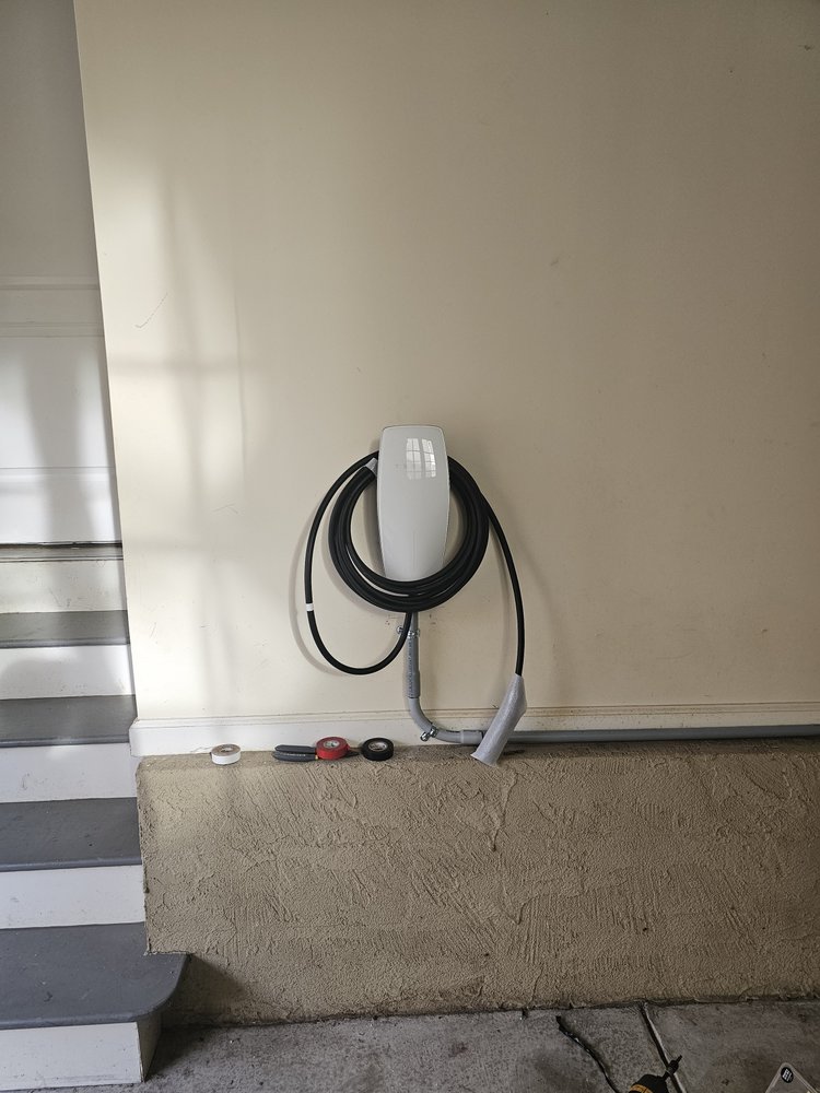 Wall-mounted EV charger with charging cable. Installation by Loftis Lighting & Electrical.