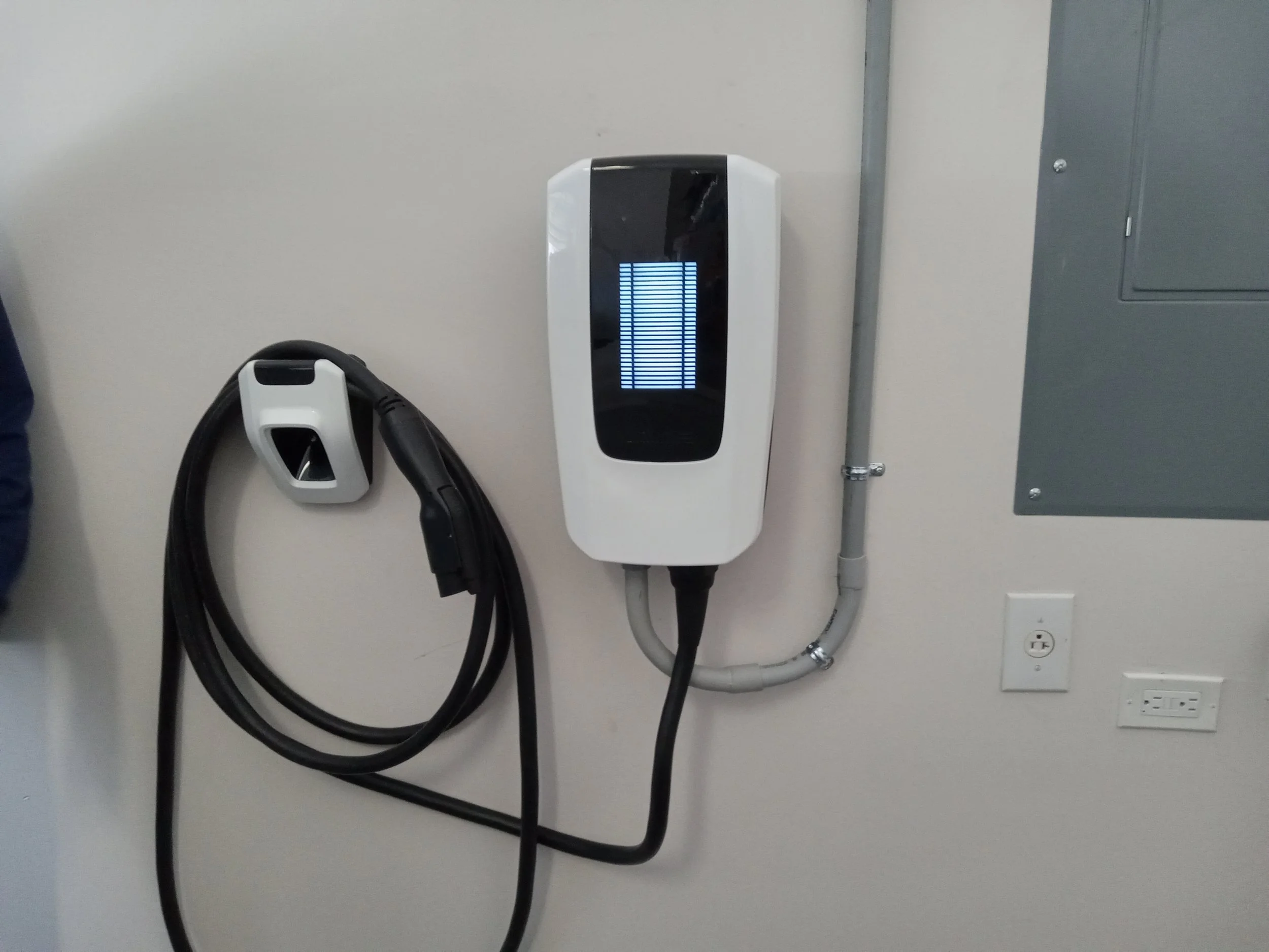 Wall-mounted home EV charger with a separate connector holder.
