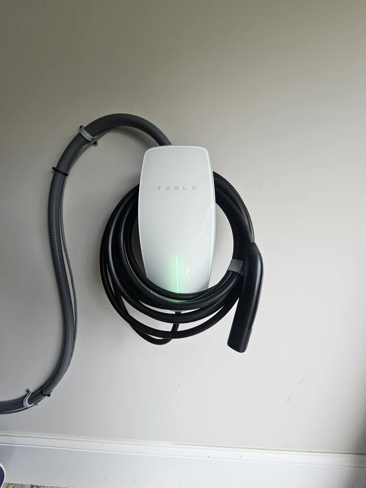 Tesla Wall Connector installation with neatly routed supply conduit and stored charging cable.