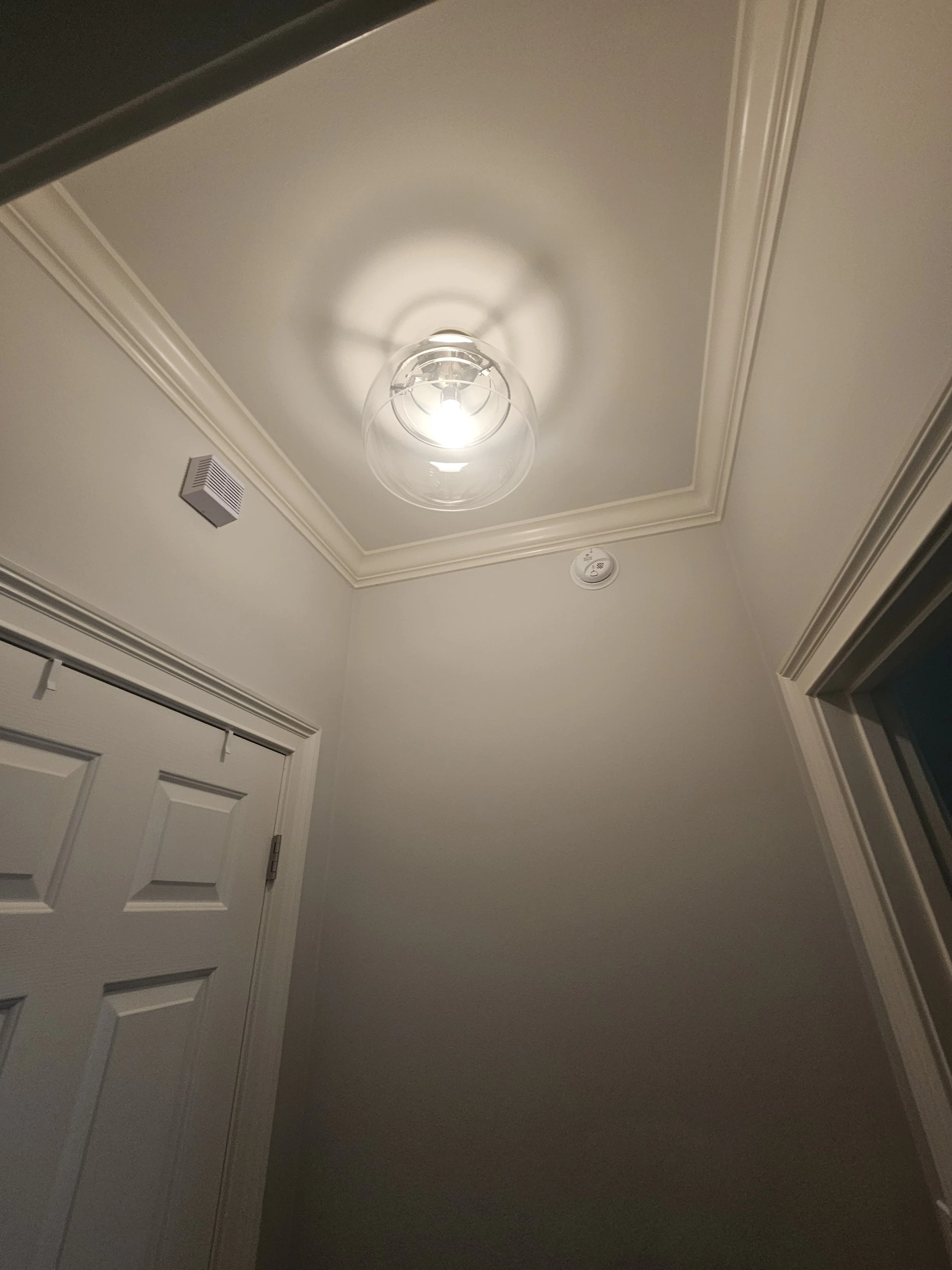 Illuminated glass ceiling fixture in a hallway. Residential light fixture installation by Loftis Lighting & Electrical.
