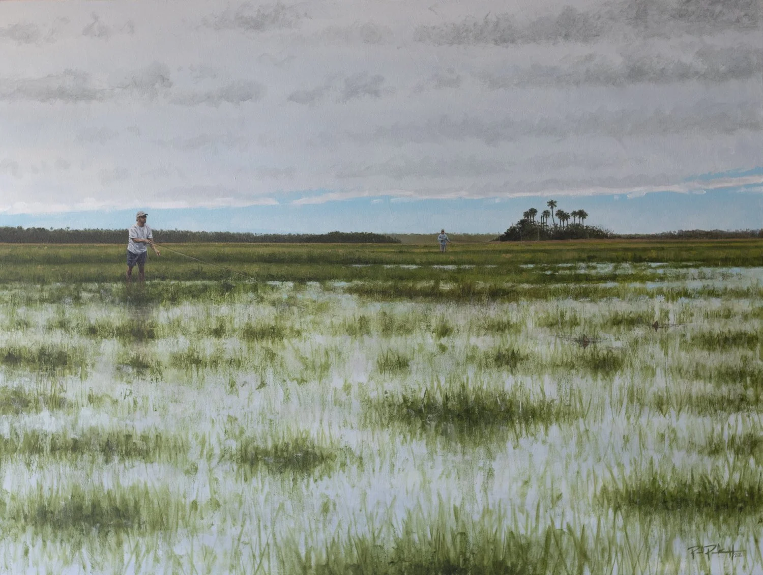 Two people standing in a flooded grassy field, with one spraying water and the other holding a stick, and a small grove of palm trees in the distance under a cloudy sky.