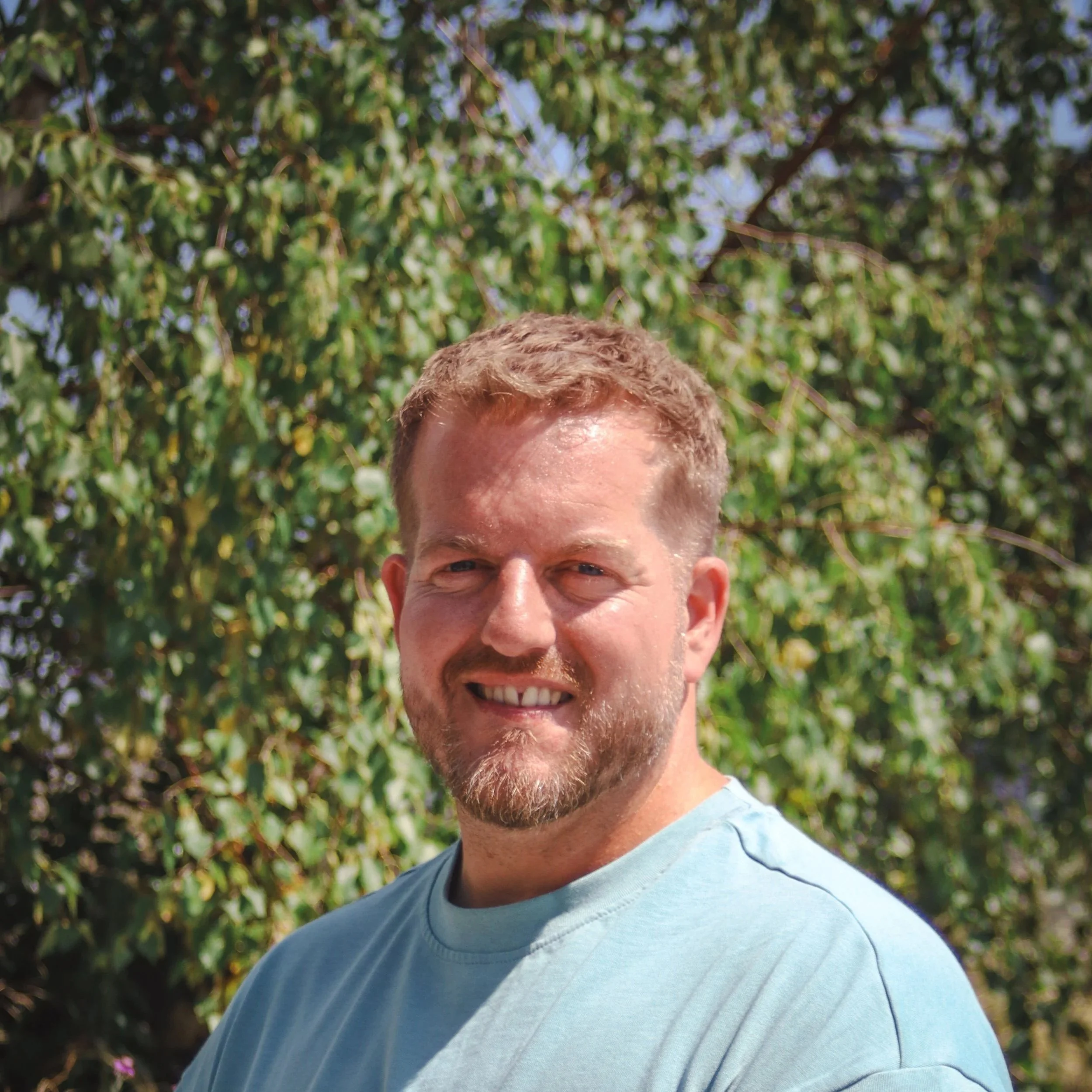 Man smiling with a wooden wall background