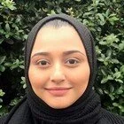 Person wearing a black hijab in front of green foliage