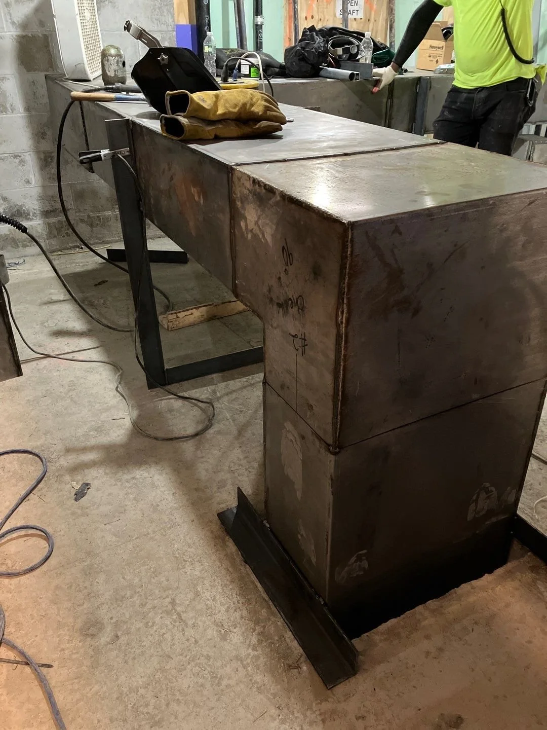 Metal workbench with tools and welding gloves in an industrial setting.