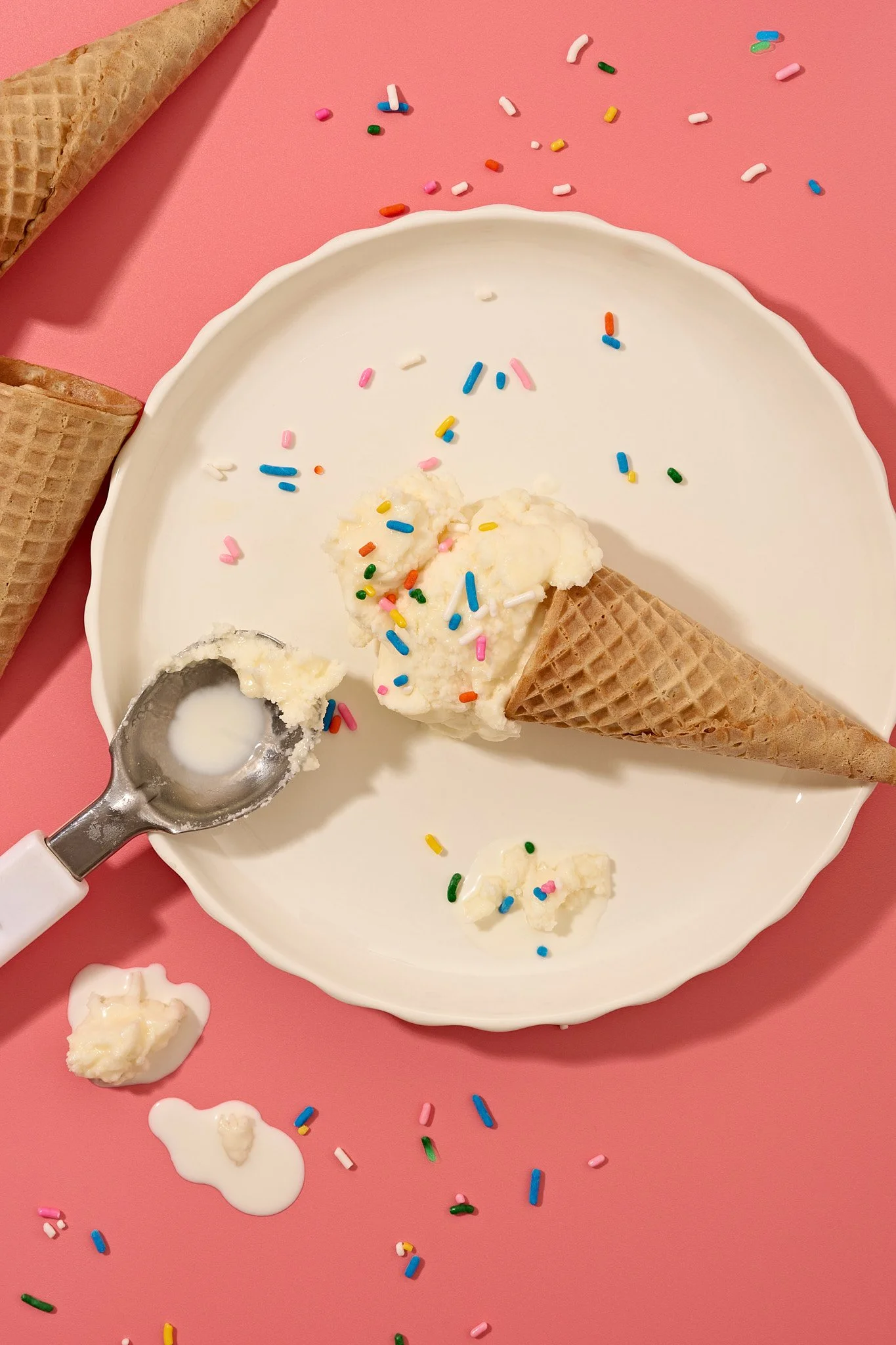 Ice cream in waffle cones with colorful sprinkles on white plate and pink background. commercial food photography product photographer freelance consumer brand 