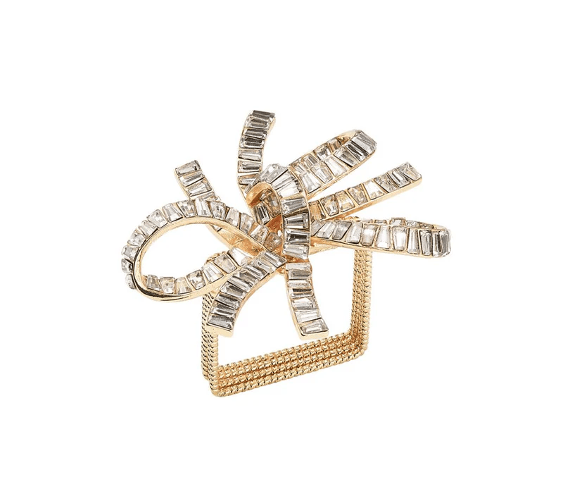 A gold and silver decorative object resembling a bow tie with a square base, adorned with rectangular clear gemstones.