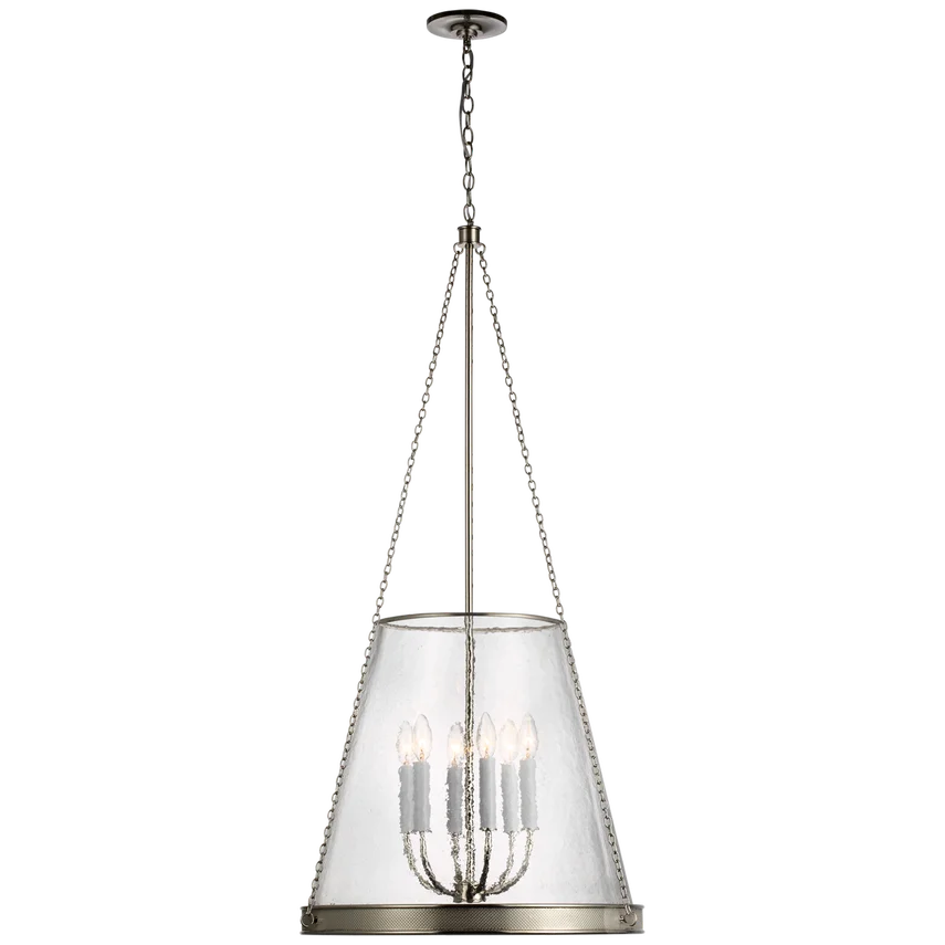 A hanging chandelier with a white, opaque drum shade and multiple candle-style light bulbs inside.