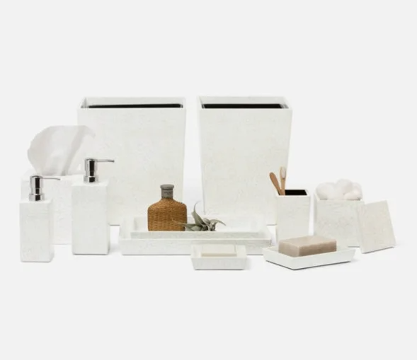 White bathroom accessories including tissue box, soap dispensers, toothbrush holder with toothbrushes, small decorative bottle, and storage containers.