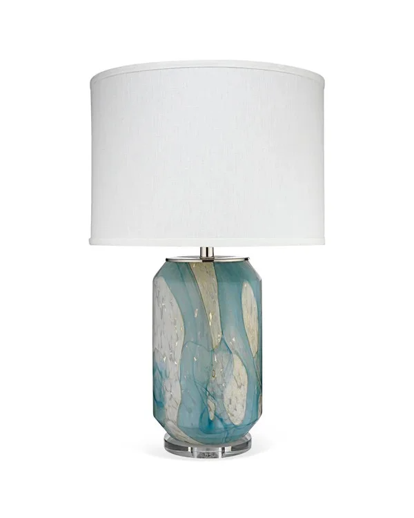 A decorative table lamp with an abstract patterned ceramic base in blue, white, gray, and beige, topped with a white fabric lampshade.