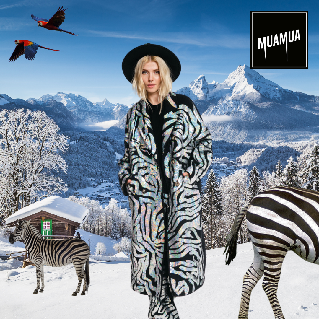 Donna con cappello nero e cappotto con disegni zebra in uno scenario di montagna ricoperta di neve, con due zebre e due pappagalli volanti nel cielo.