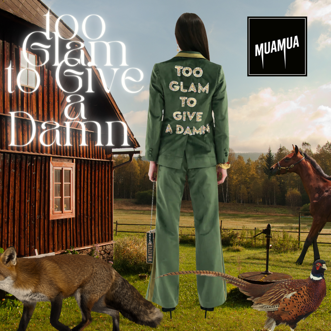 Da dietro, donna in completo verde con scritte su schiena, su campo con volpe, gallo e cavallo, e casa in legno sullo sfondo, con testo "Too Glam To Give A Damn" e logo "MUAMUA".