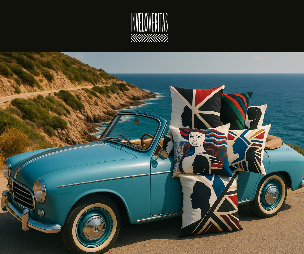 Una macchina d'epoca azzurro con diversi cuscini decorativi con disegni di volti e motivi geometrici, fermo in una strada vicino al mare con scogli e colline sullo sfondo.