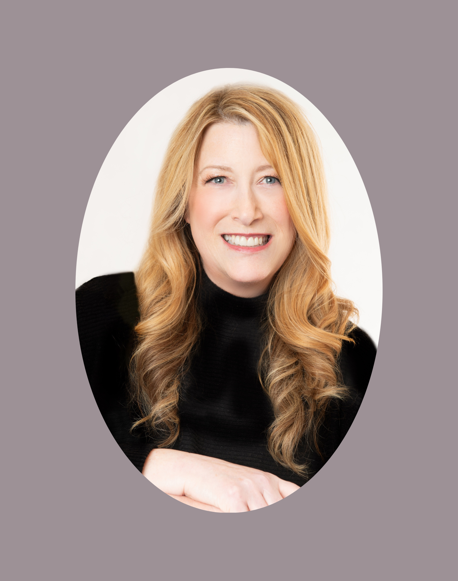 Portrait of a smiling woman with long wavy red hair, wearing a black top, against a white background with a gray border.