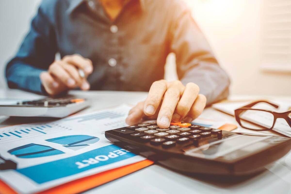 Person using calculator with financial charts on desk