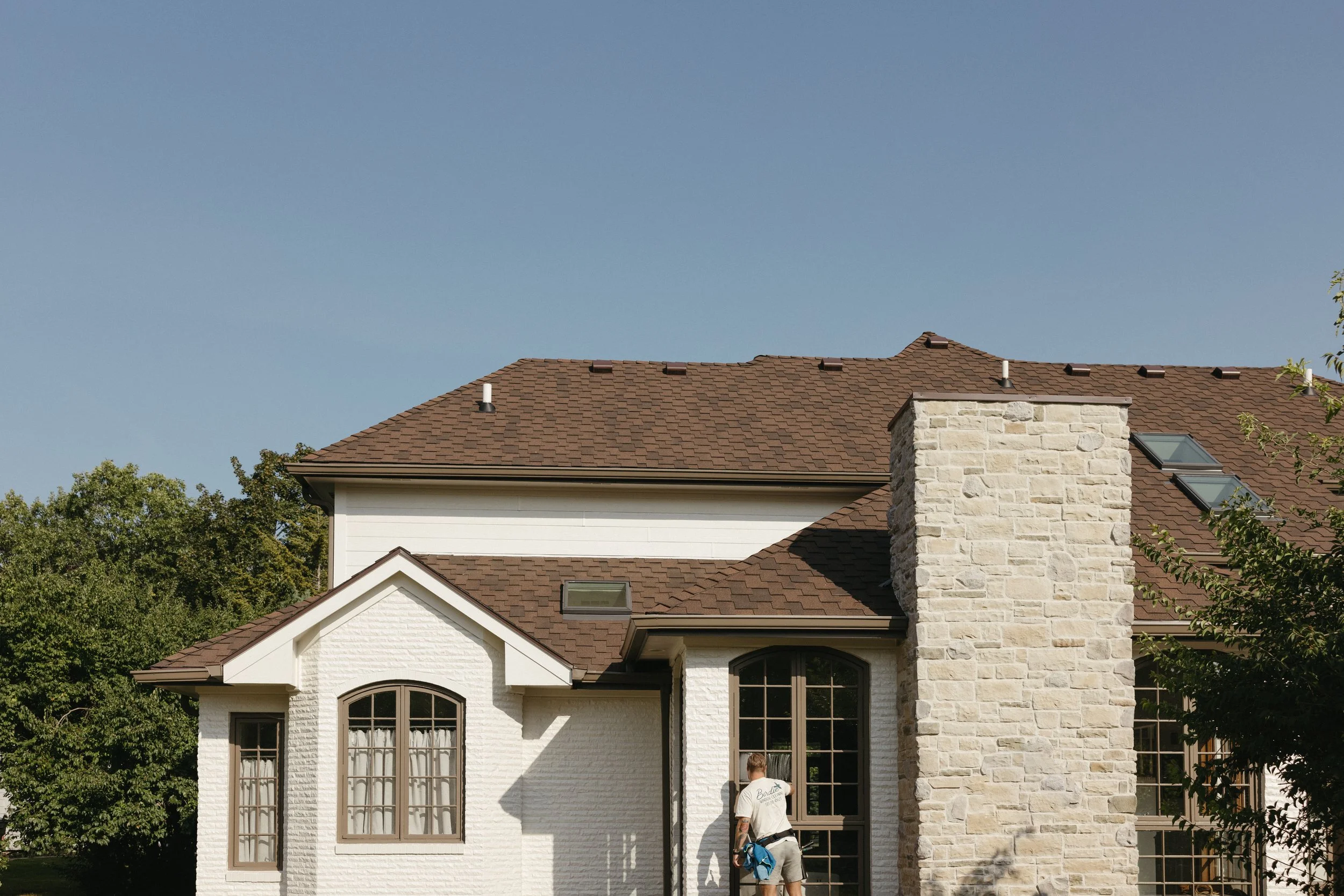 Birdie Window Cleaning technician cleaning residential window screens in Windsor Heights, IA to remove fine debris and improve their appearance.