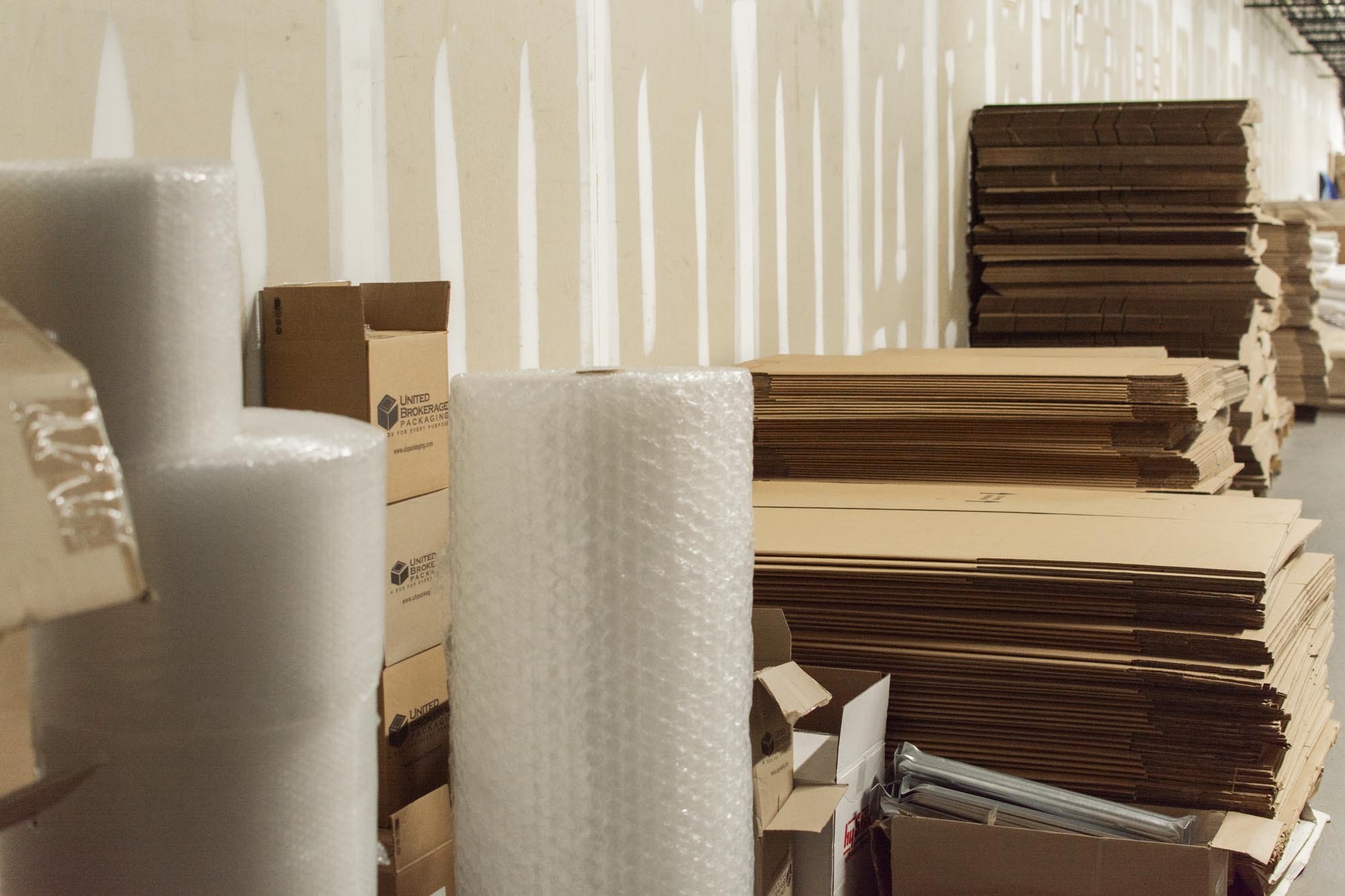 Stacks of cardboard boxes and rolls of bubble wrap in a warehouse