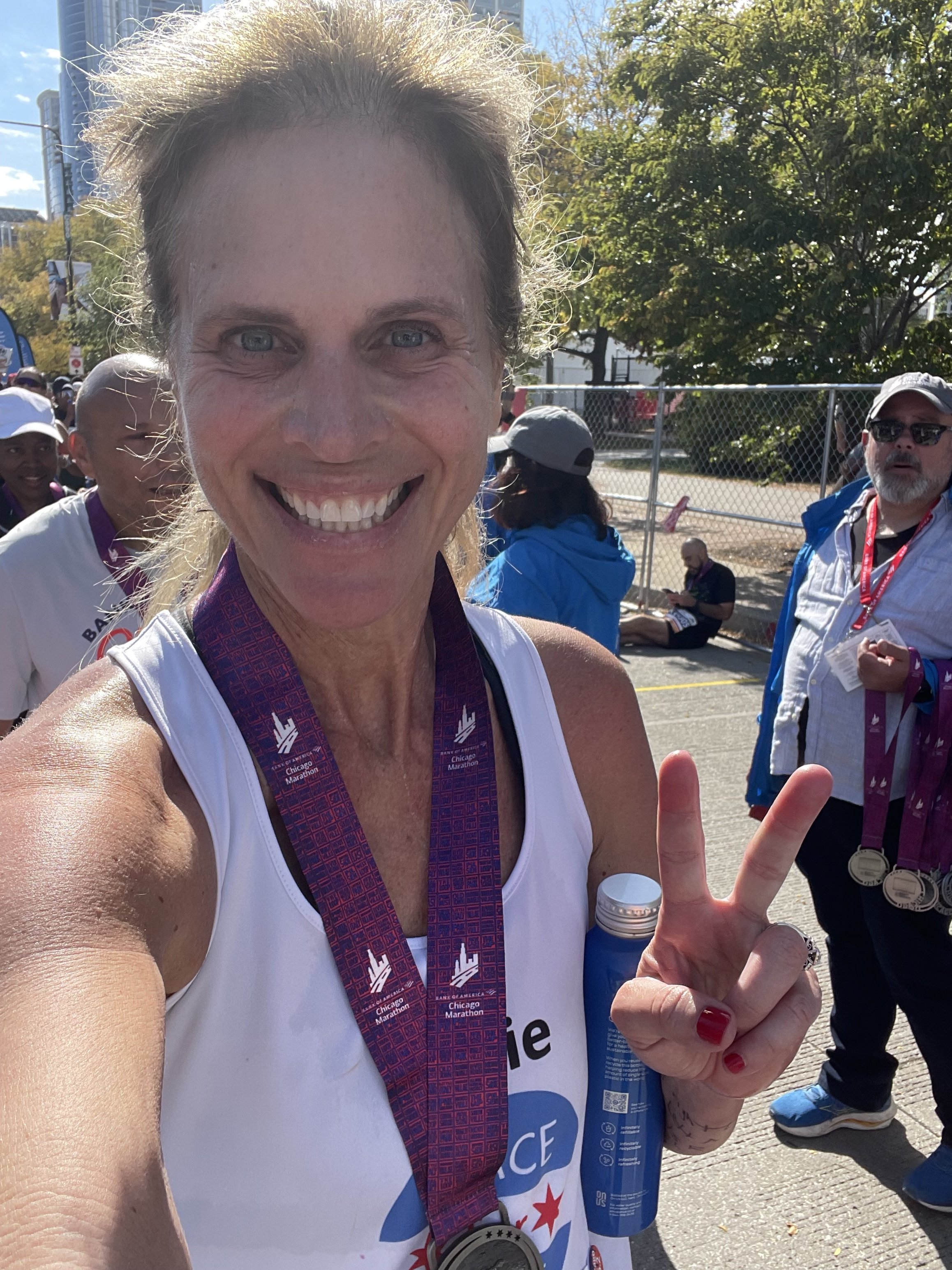 Julie Thornton holding up a peace sign while wearing her Chicago Marathon finisher medal.