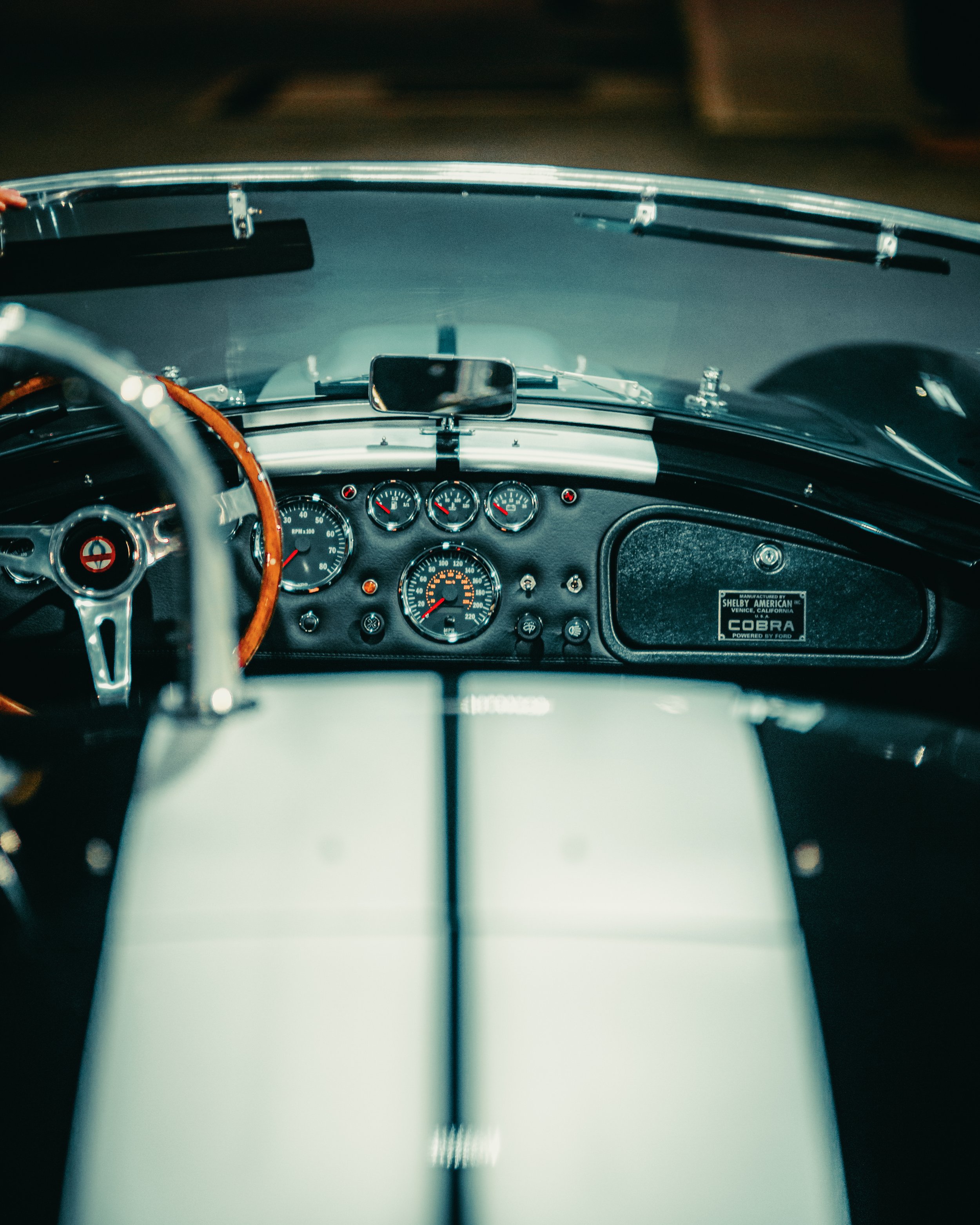 Cruscotto di un'auto sportiva classica con volante in legno e strumenti analogici visibili.