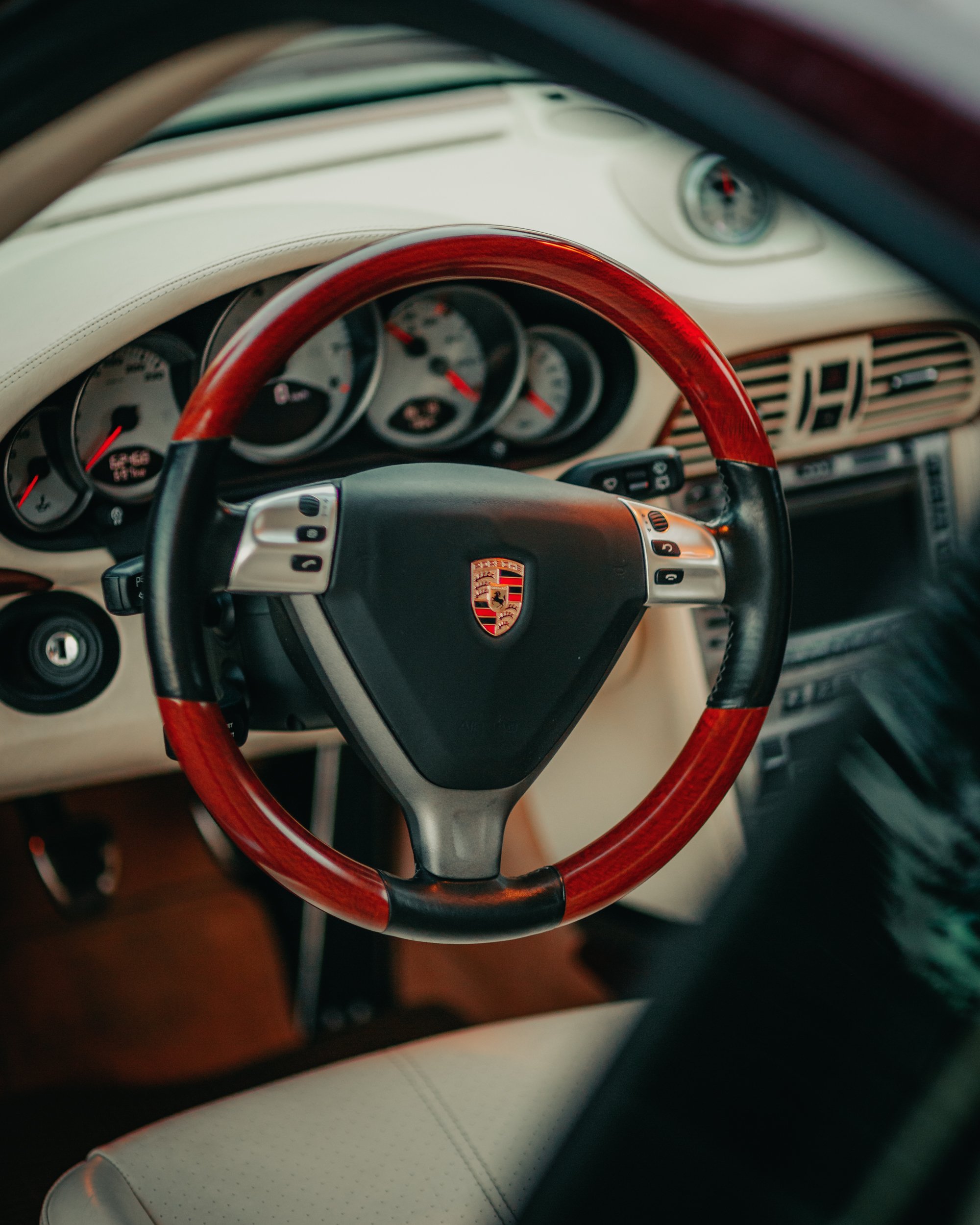 Volante di un'auto Porsche con dettagli in legno e cruscotto con strumenti.