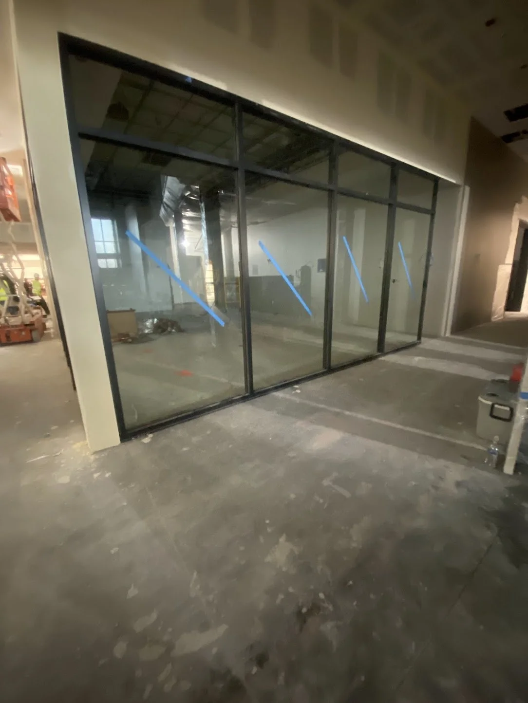 Construction site with a large glass storefront that were sealed with caulking around the perimeter of the glass with caulking.