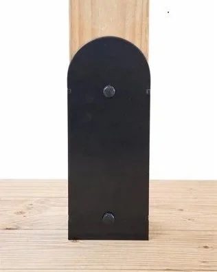 A black, rectangular mailbox with a rounded top, mounted on a wooden surface.