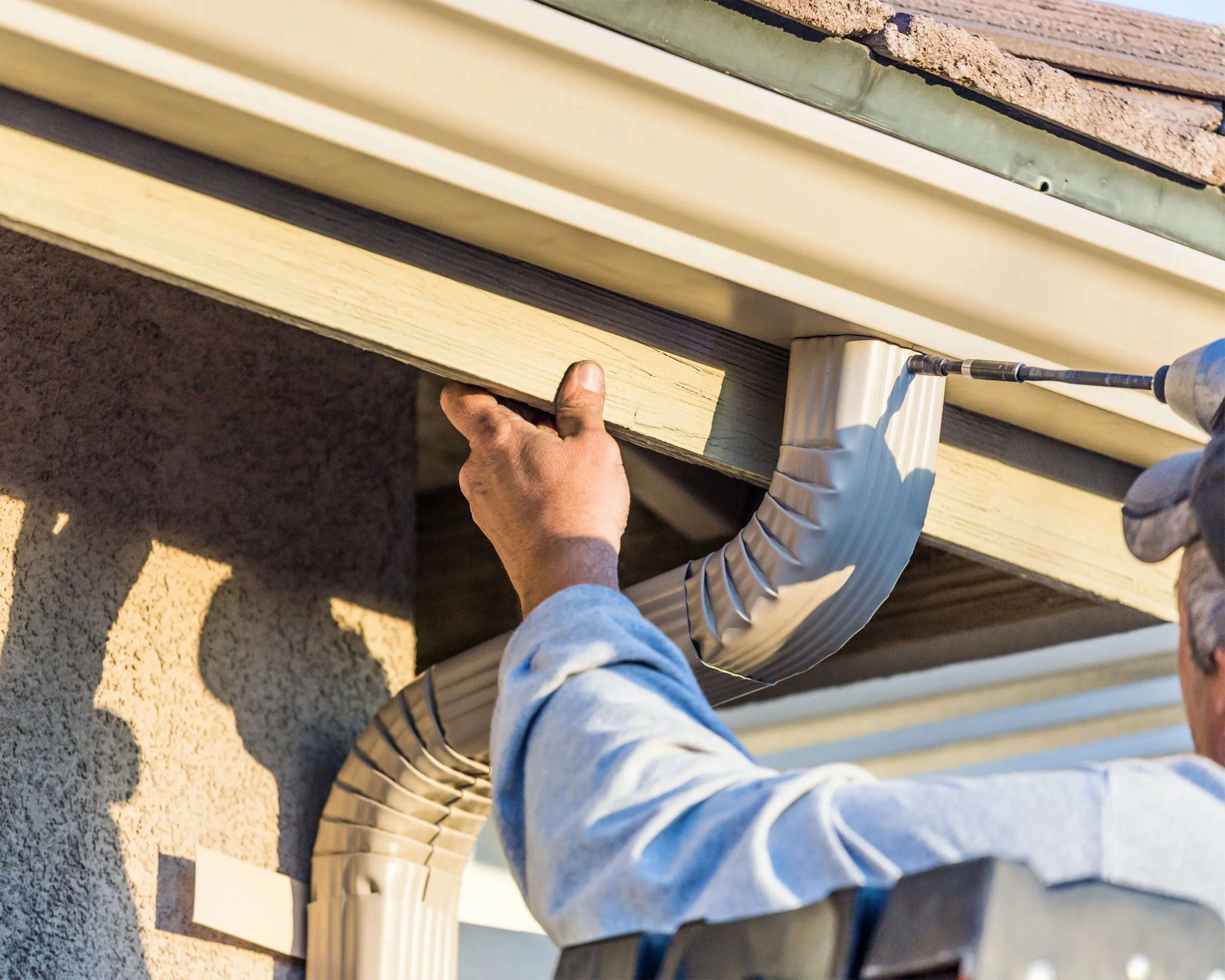 New gutter and downspout installation on a home's roof edge.