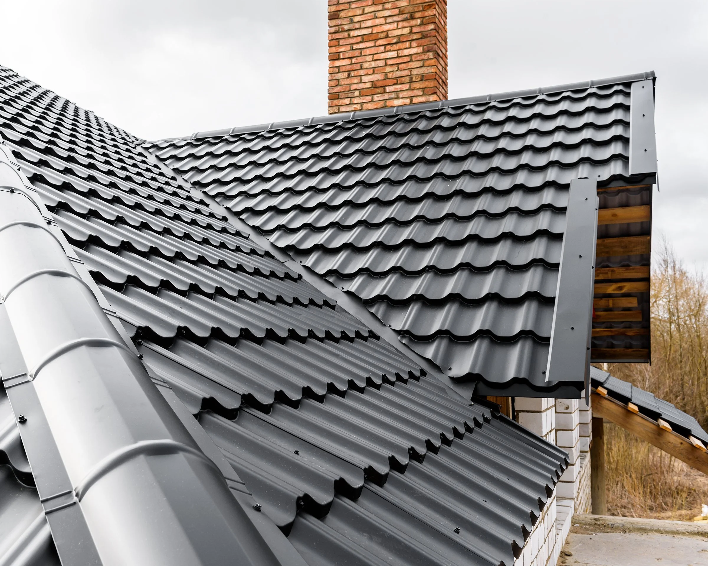 Black corrugated metal roof with a brick chimney on a residential home.