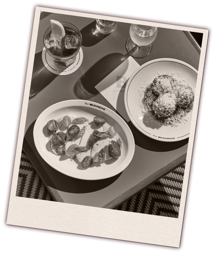 Polaroid-style photo of Bar Bianchi dishes including a Caprese salad with tomatoes and mozzarella, a plate of meatballs, a negroni, and a glass of white wine