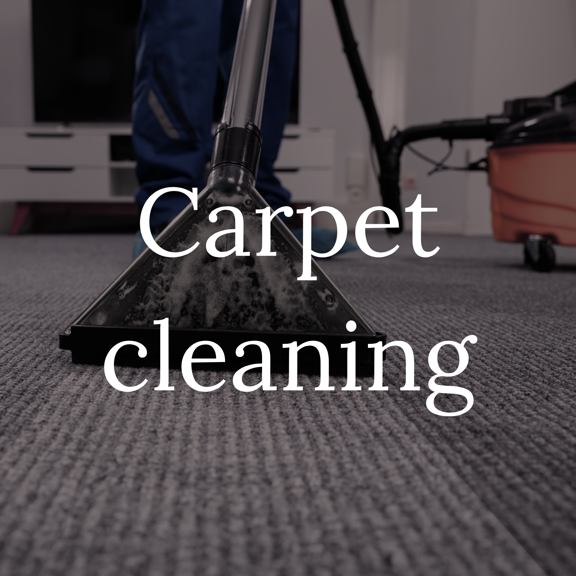 Close-up of carpet cleaning equipment with carpet cleaning machine in the background and a person operating it.