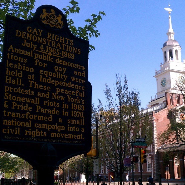 Shot of a historic marker describing gay rights demonstrations held at Independence Hall. Independence Hall is shown in the background