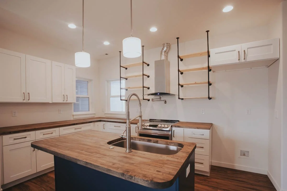 Custom kitchen with butcher block countertops and open shelving by Verity Construction.
