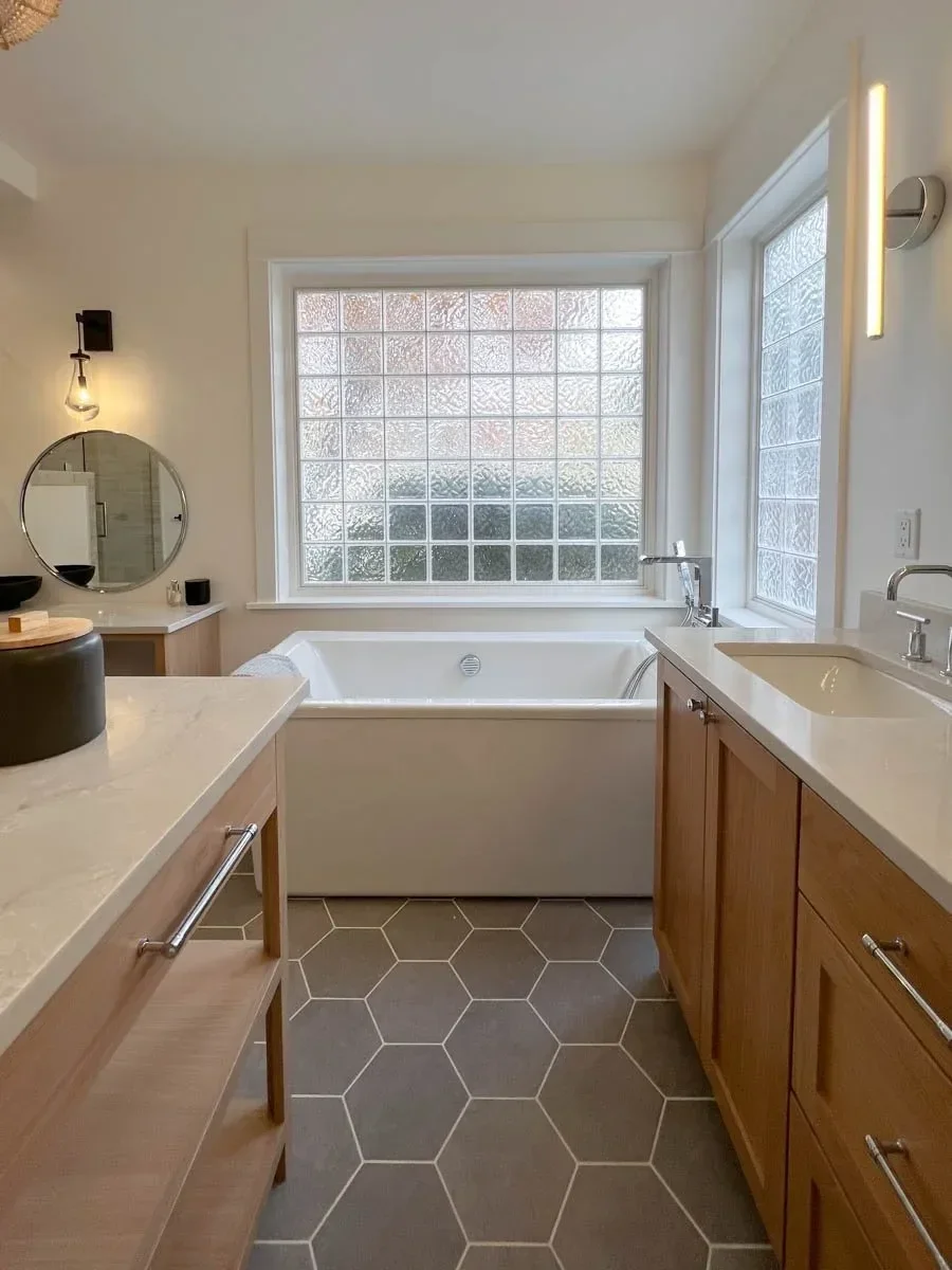Modern home renovation featuring warm wood cabinetry, hex tile flooring, textured shower walls, and neutral-toned interiors in Southern Oregon, completed by Verity Construction.