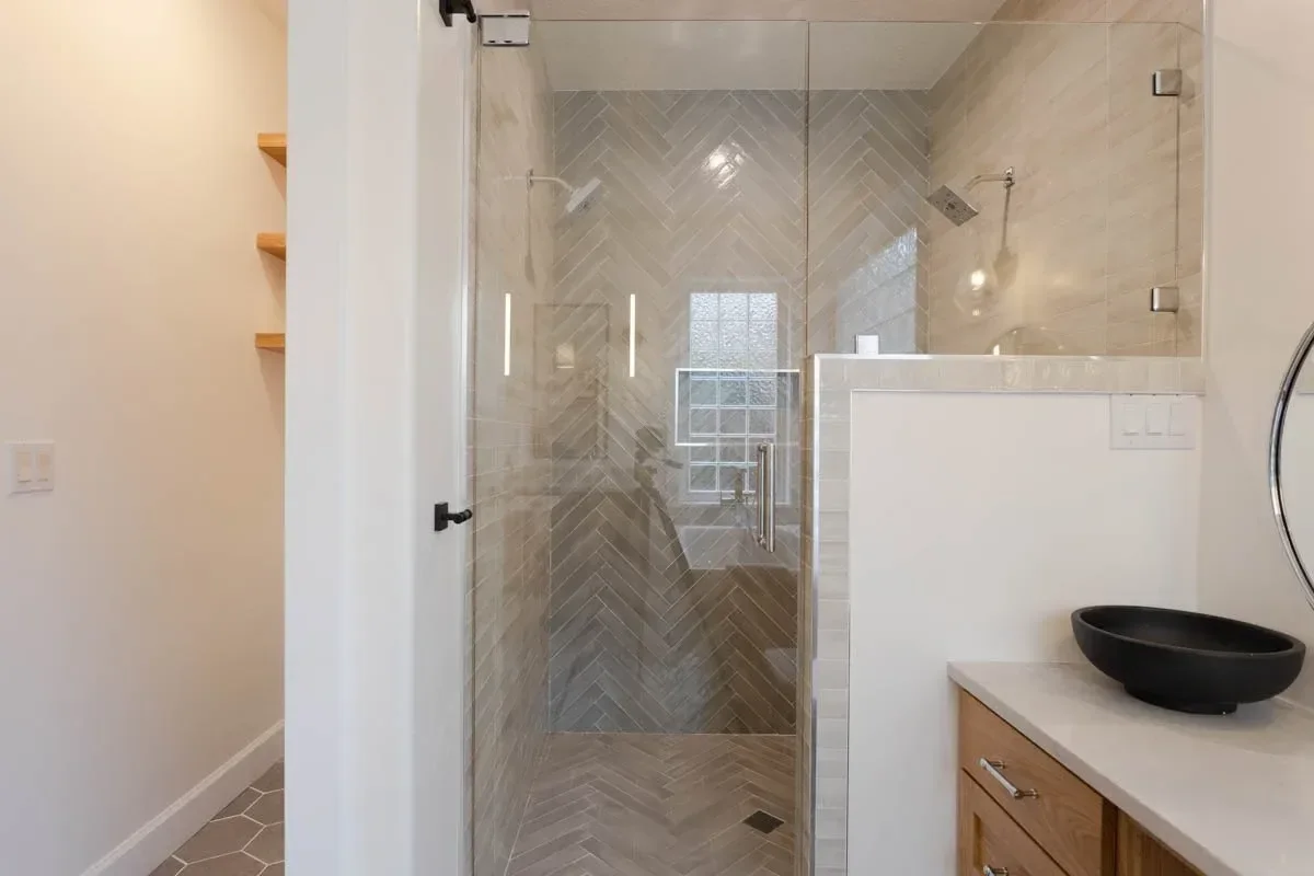Modern home renovation featuring warm wood cabinetry, hex tile flooring, textured shower walls, and neutral-toned interiors in Southern Oregon, completed by Verity Construction.