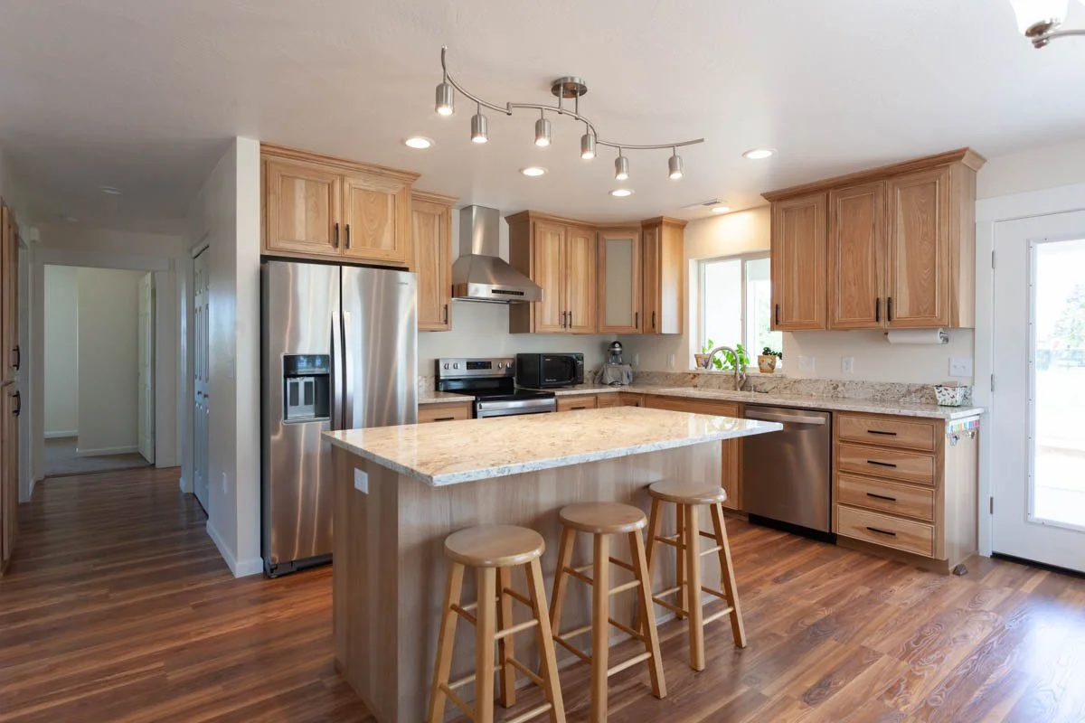Open kitchen remodel with wood floors and stainless steel appliances by Verity Construction.