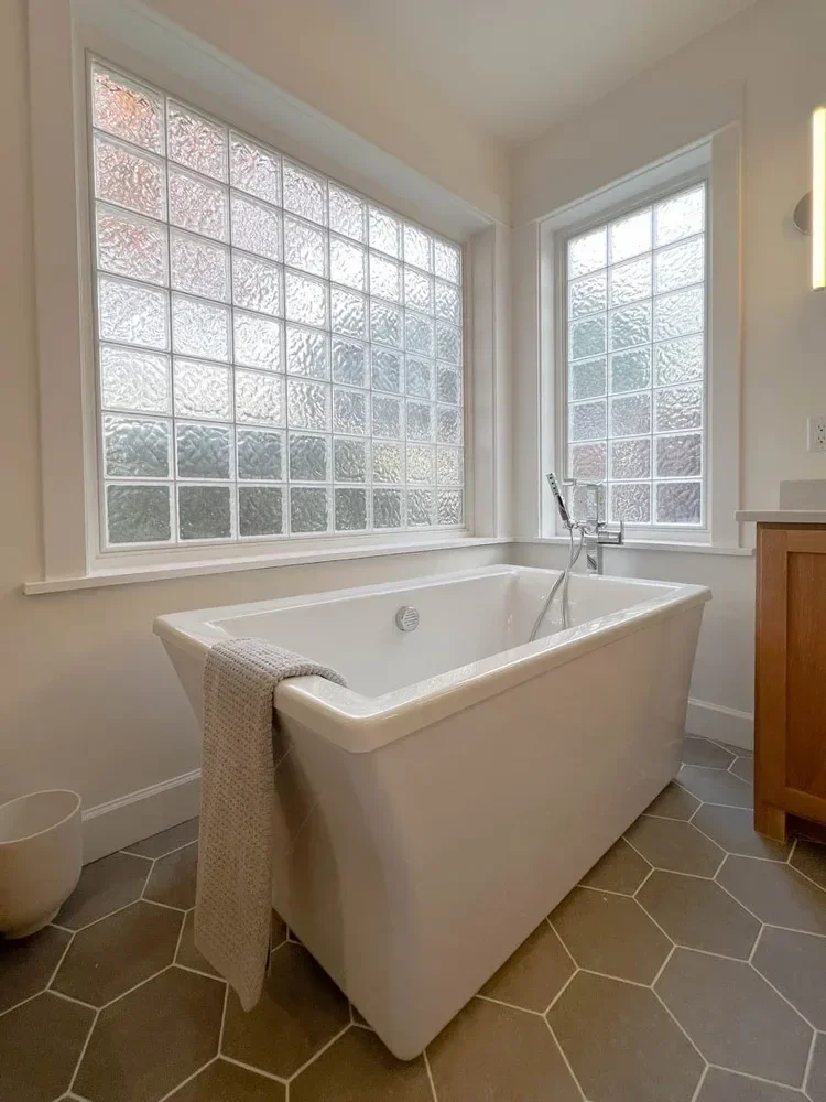 Modern home renovation featuring warm wood cabinetry, hex tile flooring, textured shower walls, and neutral-toned interiors in Southern Oregon, completed by Verity Construction.