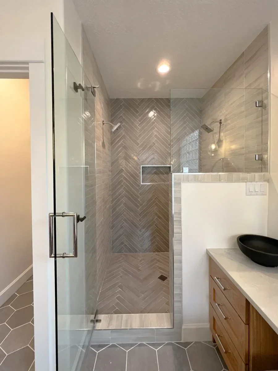 Modern home renovation featuring warm wood cabinetry, hex tile flooring, textured shower walls, and neutral-toned interiors in Southern Oregon, completed by Verity Construction.