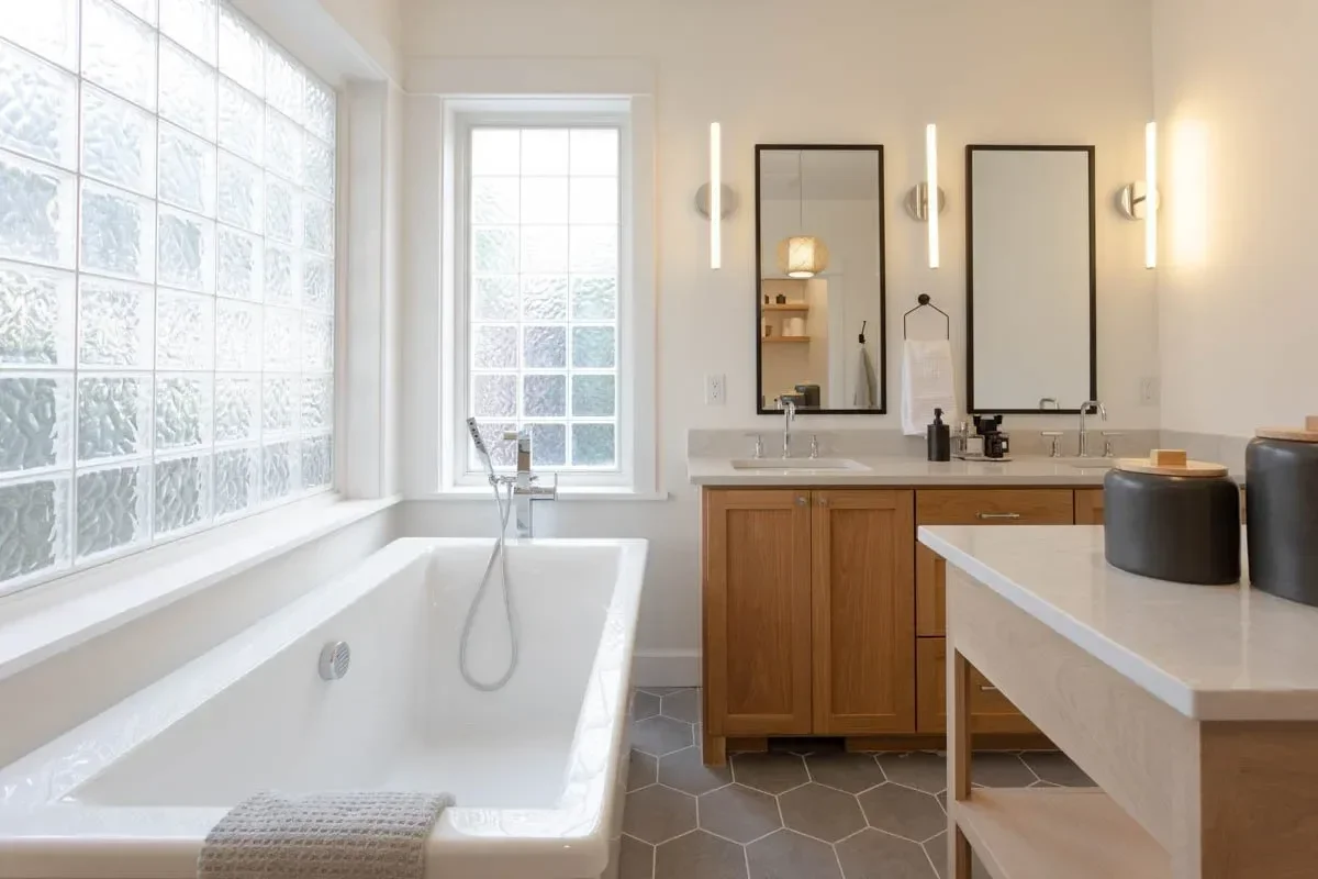 Modern home renovation featuring warm wood cabinetry, hex tile flooring, textured shower walls, and neutral-toned interiors in Southern Oregon, completed by Verity Construction.