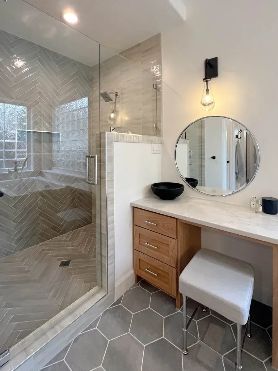 Modern home renovation featuring warm wood cabinetry, hex tile flooring, textured shower walls, and neutral-toned interiors in Southern Oregon, completed by Verity Construction.