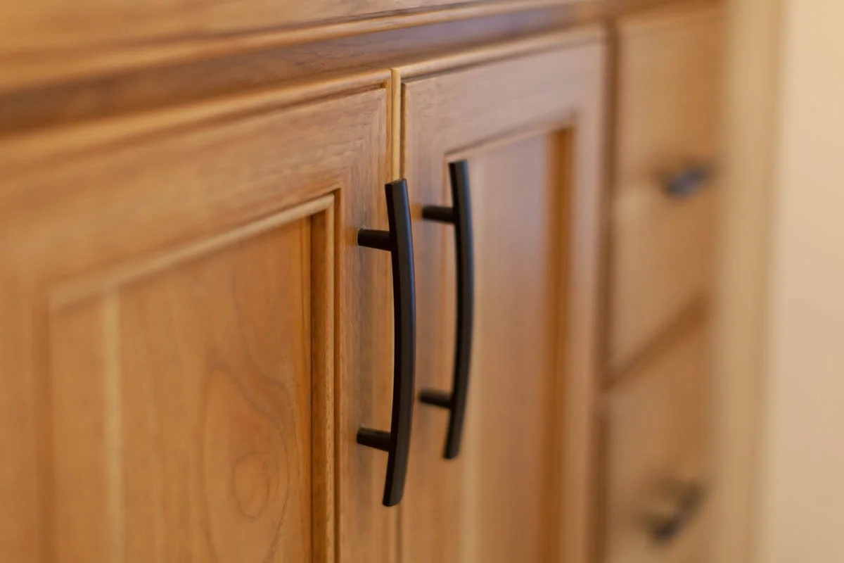 Close-up of custom wood cabinetry and matte black hardware by Verity Construction.