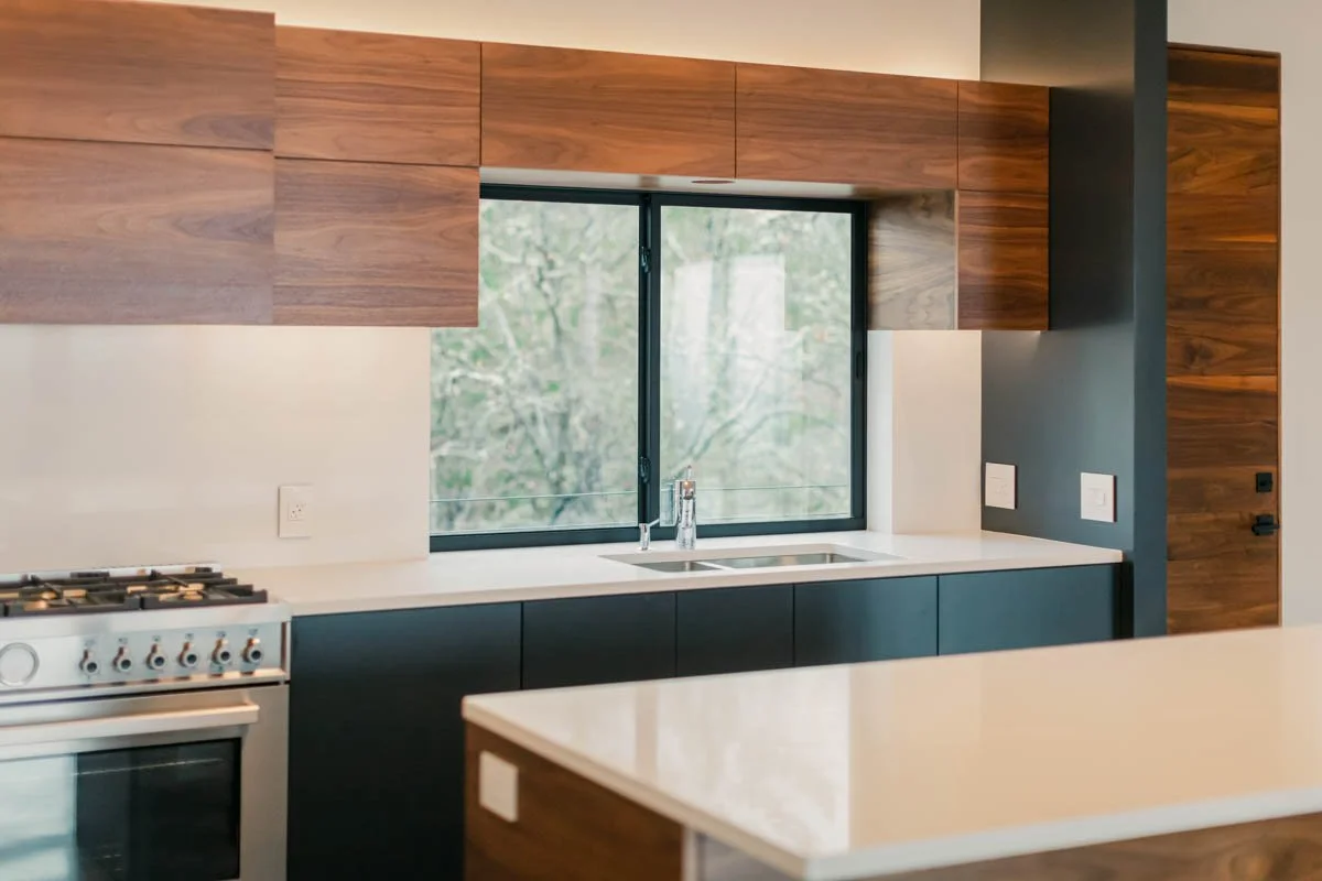 Modern kitchen featuring walnut cabinetry and white countertops, crafted by Verity Construction in Medford, Oregon.